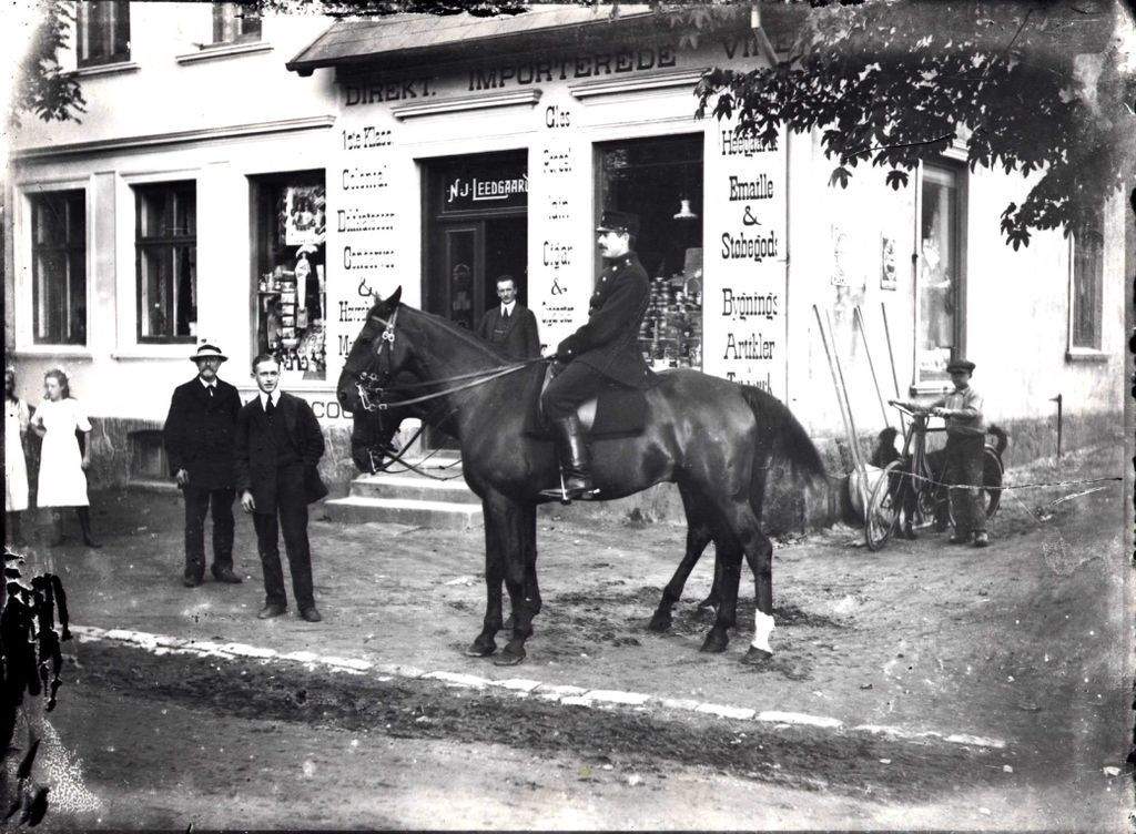 ca. 1915 Tolderne besøger Hornbæk. William Leedgaard i forretningsdøren og Carl Rasmussen Gemüsen beundrer hesten.